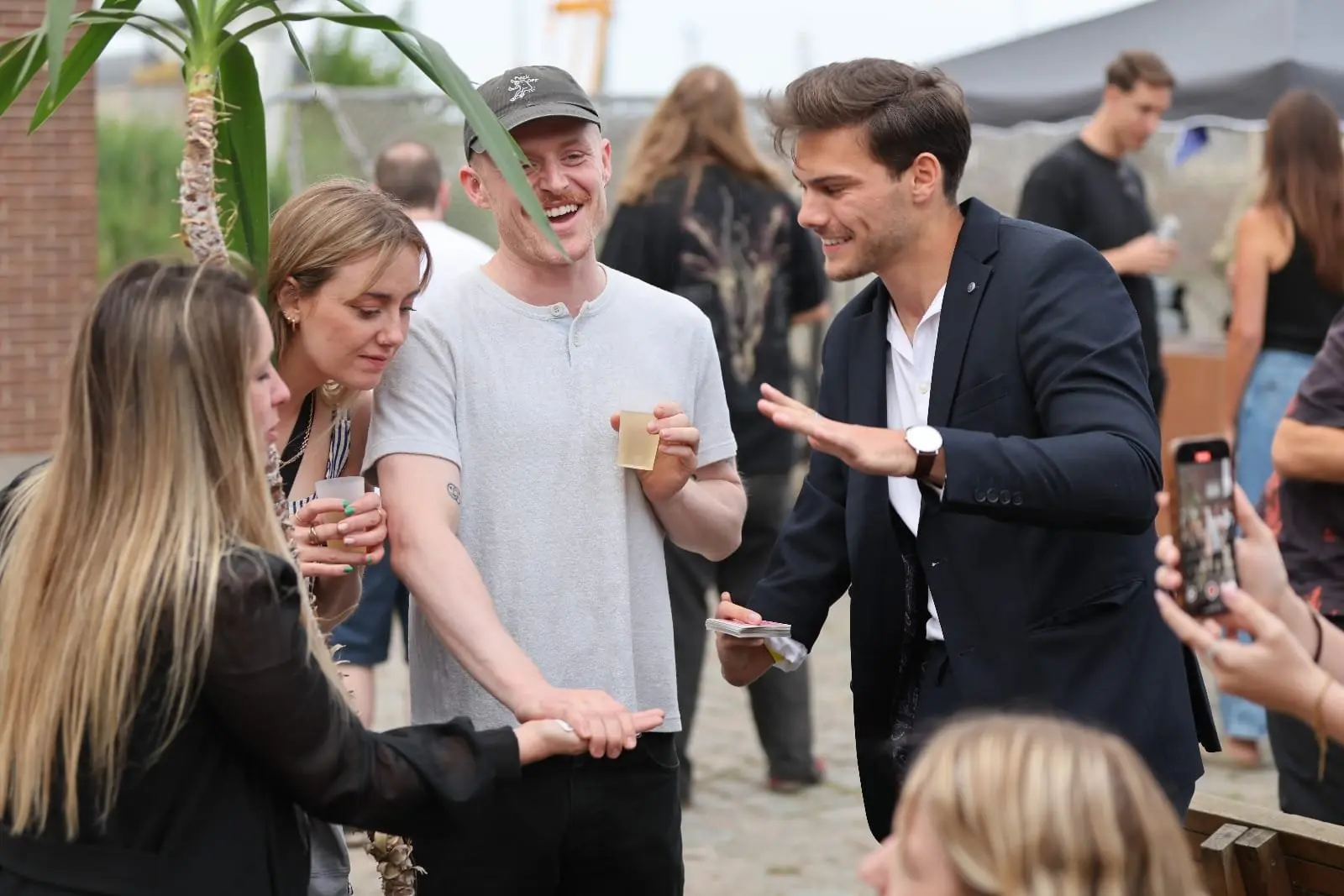 Goochelaar voert een interactieve kaarttruc uit voor enthousiaste gasten tijdens een buitenevent