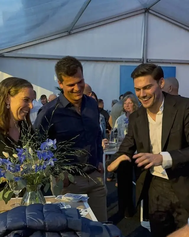 Lachende gasten volgen een interactieve kaarttruc in een tent